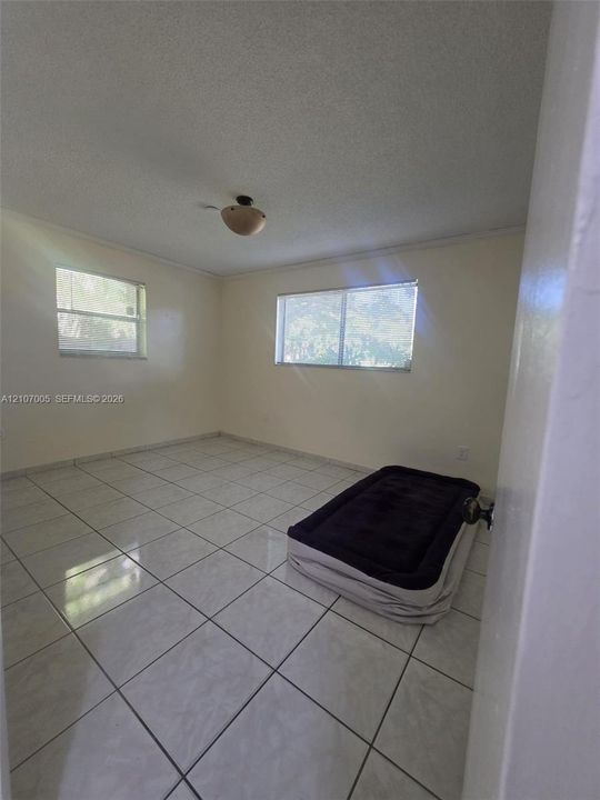 Neutral-toned interior featuring ceramic tile flooring, dual windows, and a flush-mount light fixture