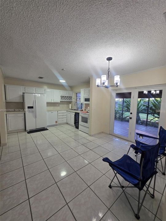Kitchen featuring white cabinetry, built-in wine storage, tile flooring, five-light chandelier, and glass-paneled double doors
