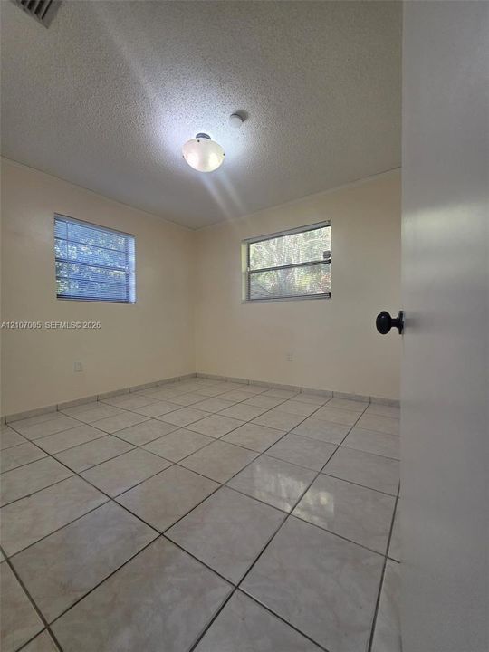Room featuring neutral-toned ceramic tile flooring, dual-pane horizontal sliding windows, and a central flush-mount dome light fixture