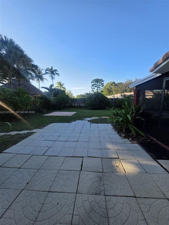 Private backyard featuring a paved patio, manicured lawn, established landscaping, and perimeter fencing