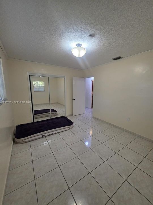 Ceramic tile flooring, sliding mirror-paneled closet doors, and a flush-mount ceiling light fixture