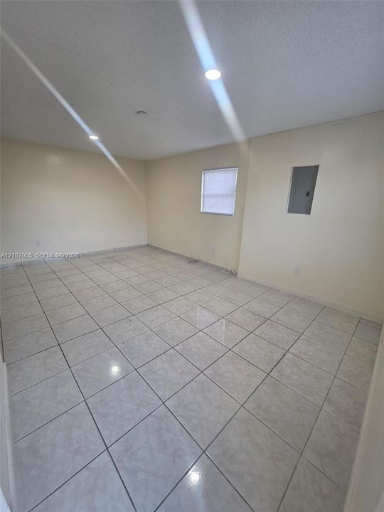 Neutral-toned ceramic tile flooring, recessed ceiling lighting, and a single-pane window with installed blinds