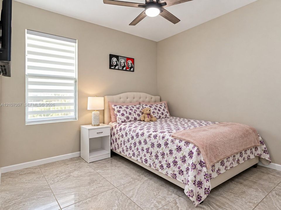 Room featuring large-format tile flooring, a dual-tone window shade, and a ceiling fan with integrated lighting