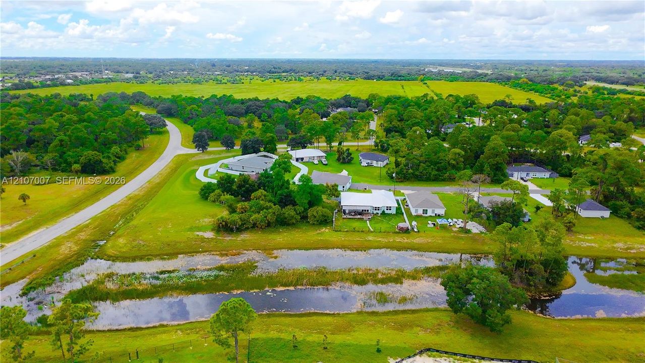Aerial perspective showcasing expansive acreage, mature tree clusters, and a natural waterway border