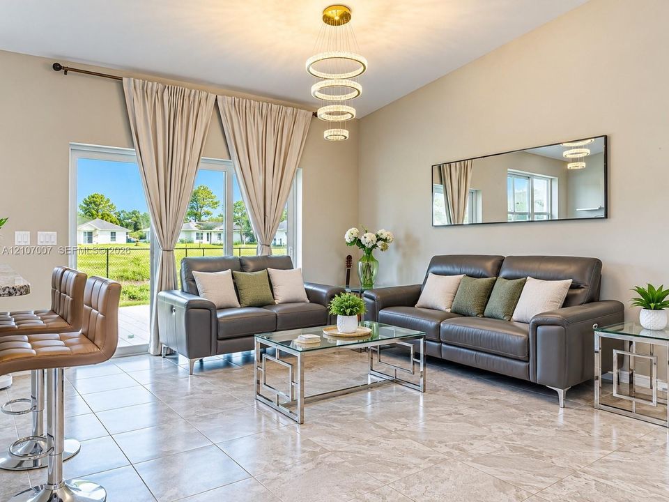 Vaulted ceilings, multi-tiered ring chandelier, large glass sliding doors, and neutral-toned tile flooring