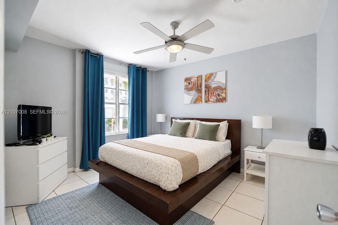 Light-filled room featuring large format tile flooring, a multi-blade ceiling fan with integrated lighting, and a multi-pane window