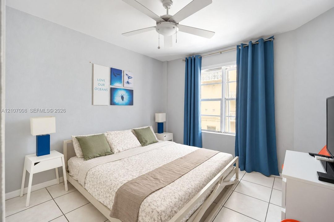 Neutral-toned room featuring a central ceiling fan with integrated lighting, tile flooring, and a multi-pane window