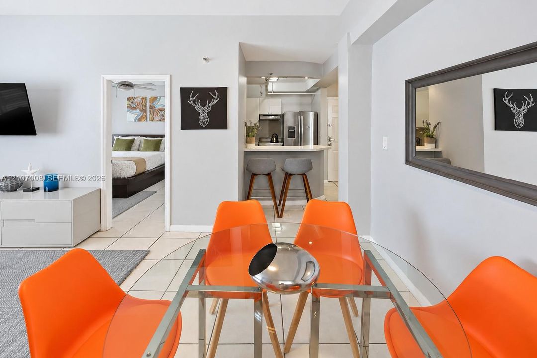 Open-concept interior featuring large-format tile flooring, kitchen with stainless steel appliances, breakfast bar, and wall-mounted mirror
