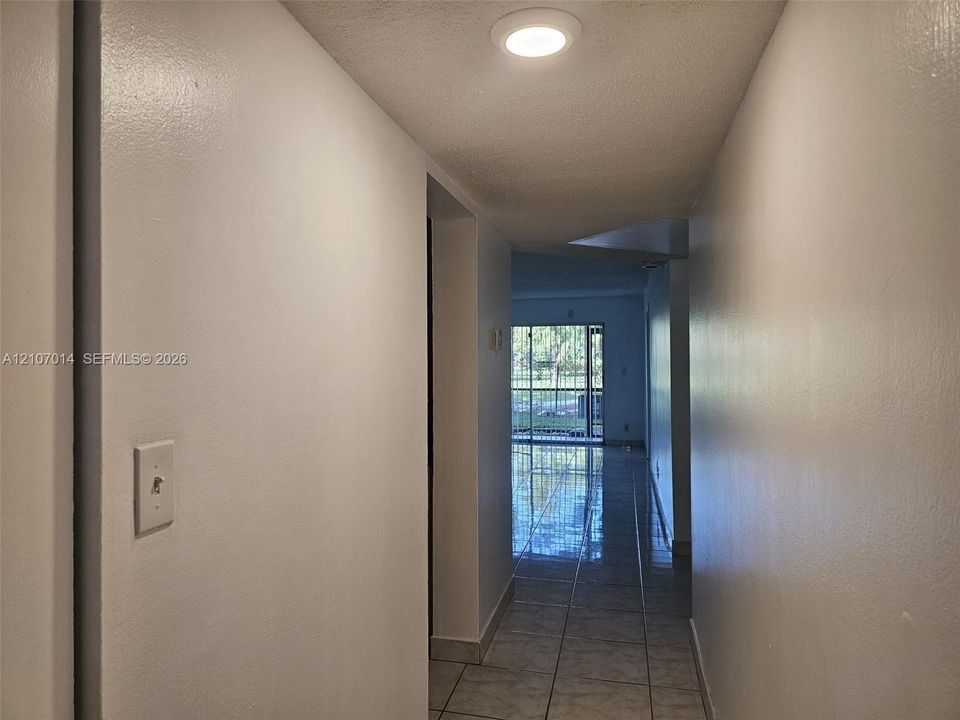 Interior hallway featuring smooth-finish walls, tile flooring, and a recessed ceiling light fixture