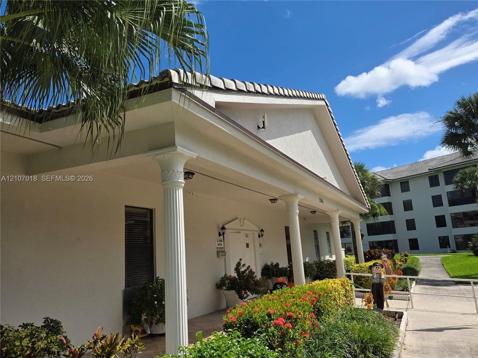 Exterior facade featuring a covered entryway with classic columns, a pitched tile roof, and a textured stucco finish