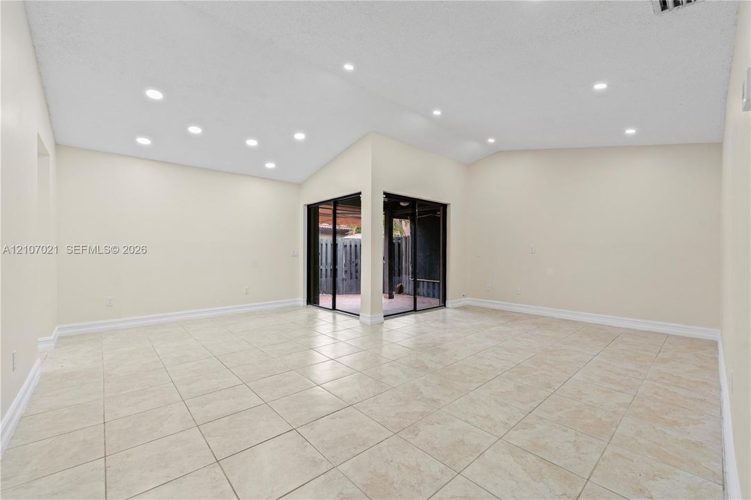 Vaulted ceiling featuring recessed lighting, ceramic tile flooring, and sliding glass doors opening to an exterior patio