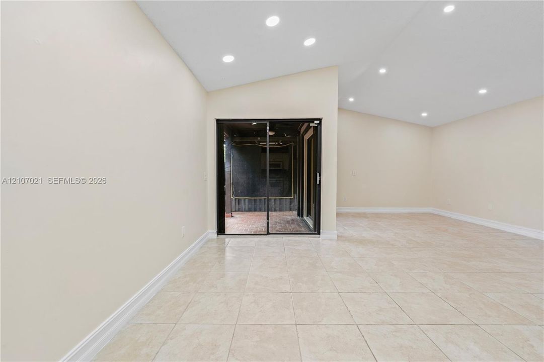 Vaulted ceilings with recessed lighting, tile flooring, and sliding glass door access to a covered patio