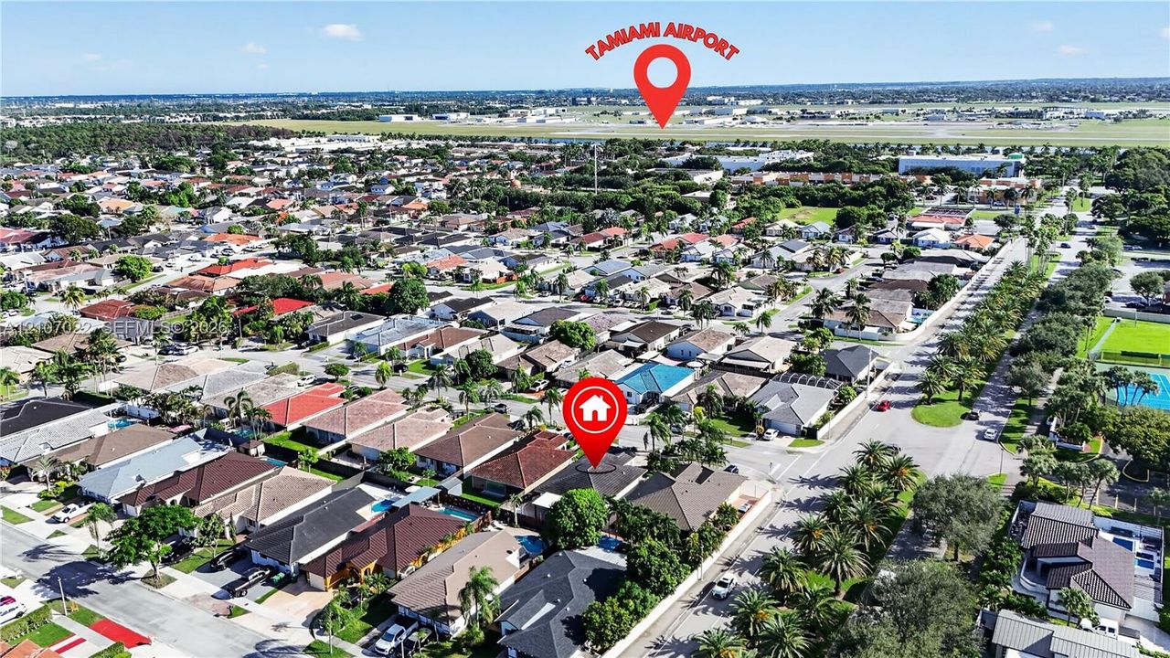 Aerial perspective of a residential neighborhood featuring paved streets, mature canopy trees, and proximity to regional aviation infrastructure