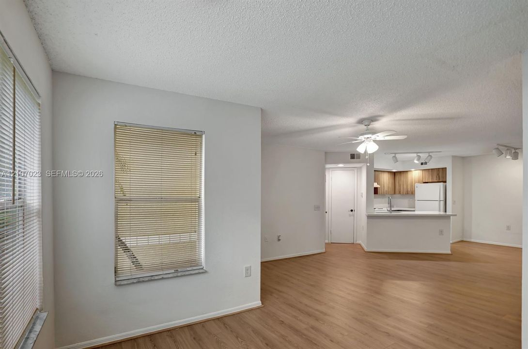 Open-concept interior featuring wood-finish flooring, a ceiling fan with integrated lighting, track lighting, and a kitchen peninsula
