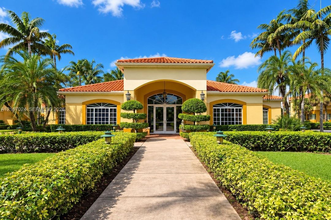 Mediterranean-style architecture featuring a tile roof, arched entryway, multi-light windows, paved walkway, and manicured landscaping