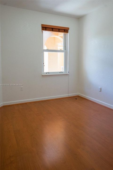 Interior space featuring smooth white walls, wood-finish flooring, and a single hung window with a wooden valance