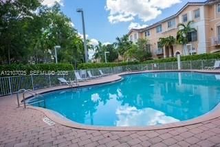 Swimming pool with a paved deck, metal perimeter fencing, and mature landscaping