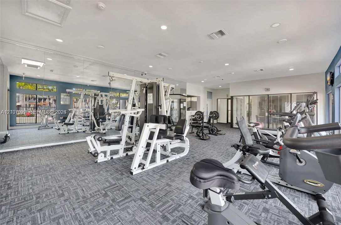 Fitness center featuring wall-to-wall mirrors, recessed lighting, and patterned industrial-grade carpeting
