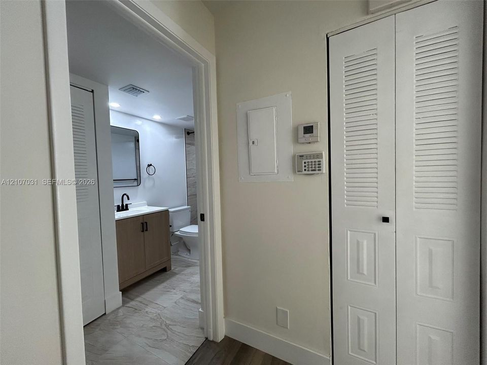 Bathroom featuring a wood-finish vanity with a white countertop, matte black faucet, and stone-finish tile flooring