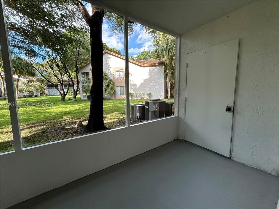 Screened-in enclosure featuring concrete flooring, a solid-core utility door, and wide-span mesh screening