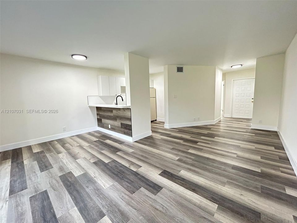 Wood-finish flooring, kitchen peninsula with wood-finish paneling, white cabinetry, matte black faucet, and flush-mount ceiling lighting