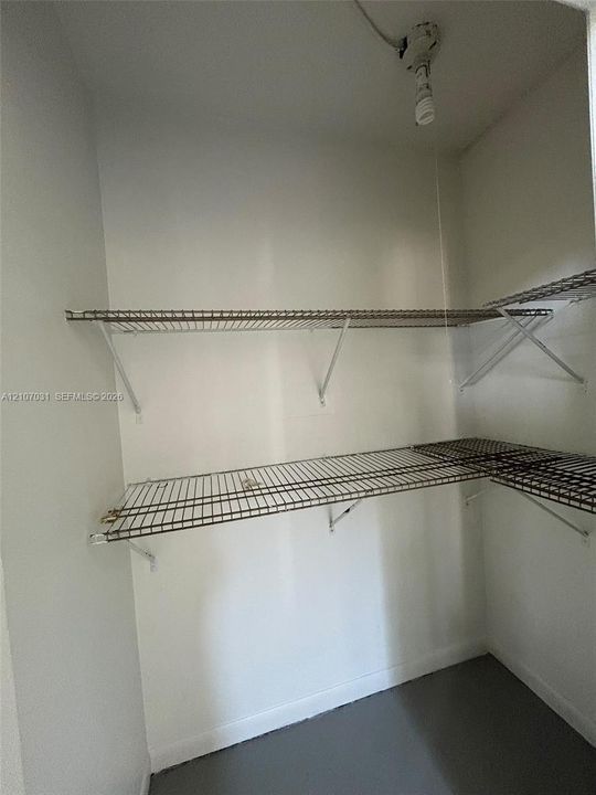 Built-in storage space featuring two levels of white wire shelving and a ceiling-mounted light fixture