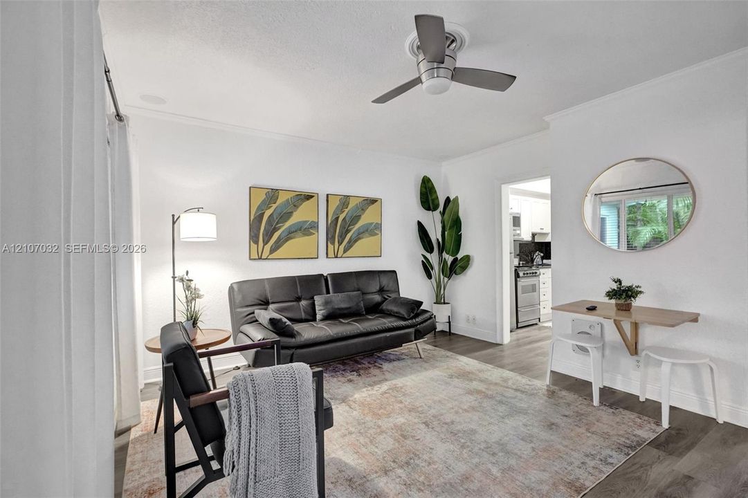 Living area featuring wood-finish flooring, a neutral color palette, and a modern ceiling fan with integrated lighting