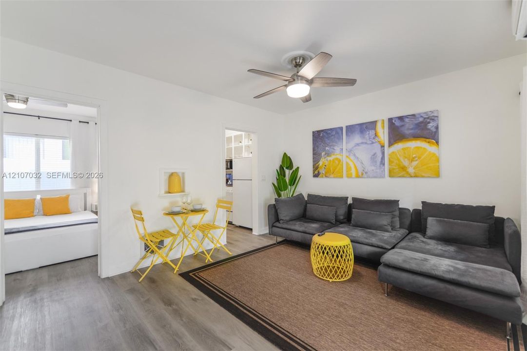 Living area featuring wood-finish flooring, a ceiling fan with integrated lighting, and a recessed wall niche