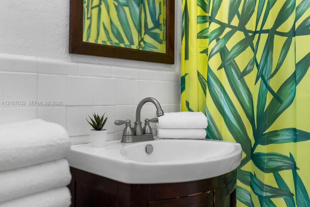 Curved wood-finish vanity featuring an integrated basin, brushed nickel dual-handle faucet, white tile backsplash, and a framed mirror
