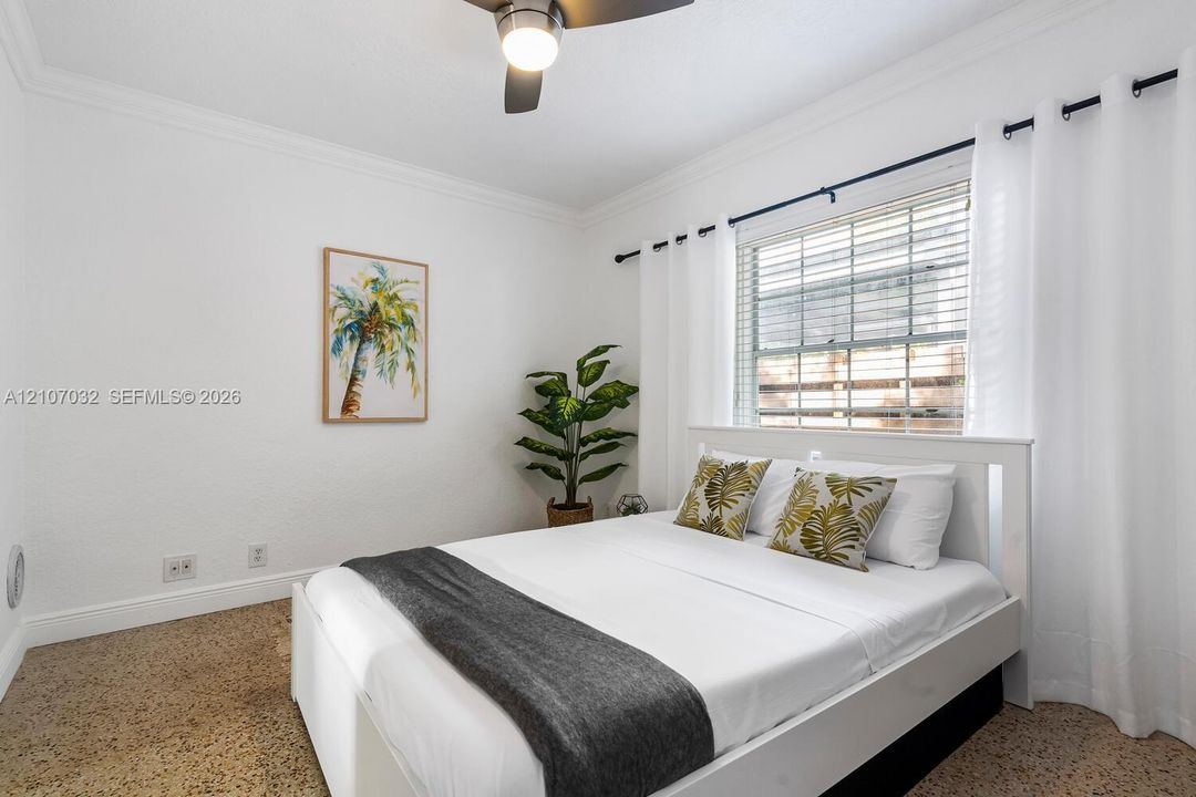 Bedroom featuring light-toned interior walls, terrazzo flooring, crown molding, and a ceiling fan with integrated lighting