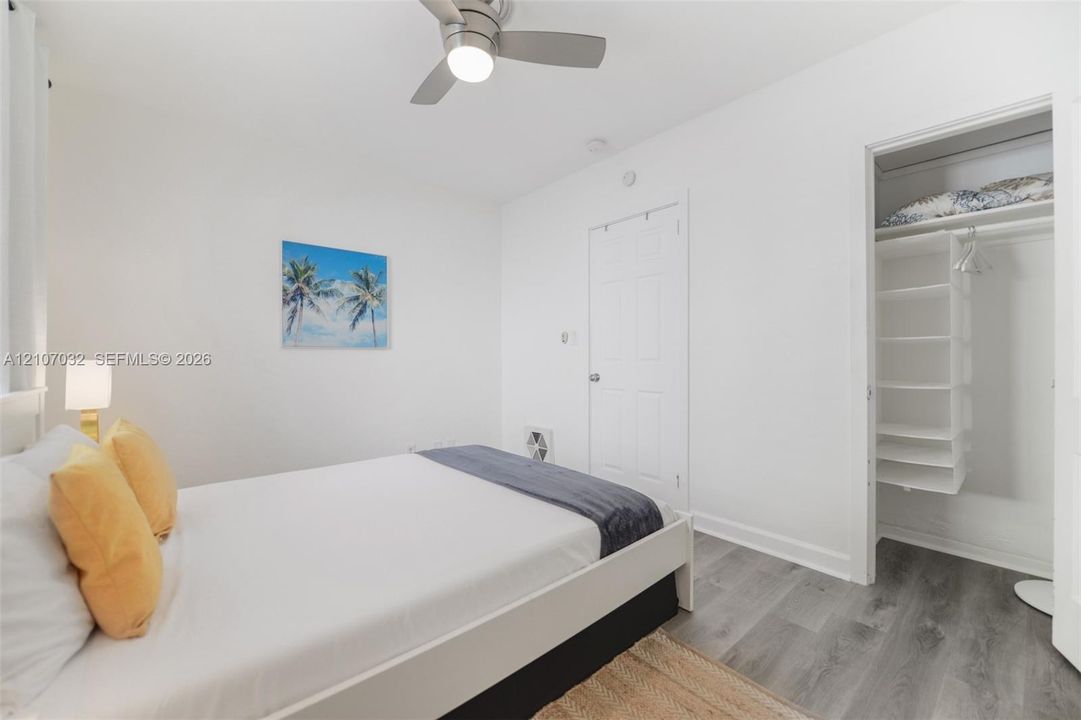 Interior space featuring wood-finish flooring, a ceiling fan with integrated lighting, and a closet with built-in shelving