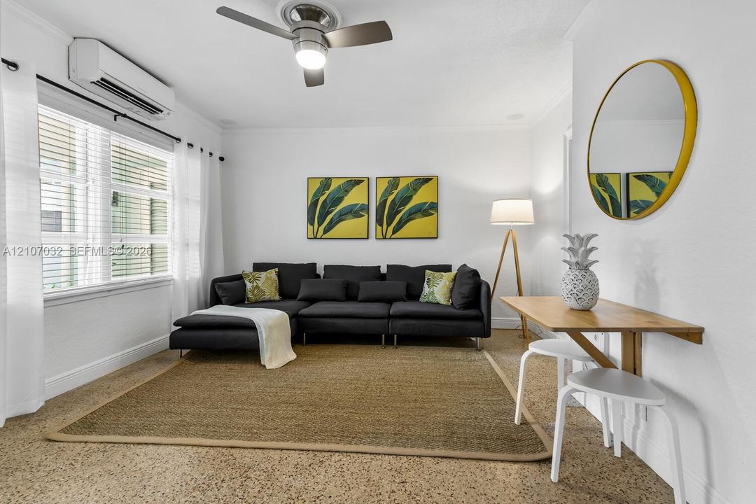 Interior space featuring speckled composite flooring, a wall-mounted ductless air conditioning unit, and a ceiling fan with integrated lighting