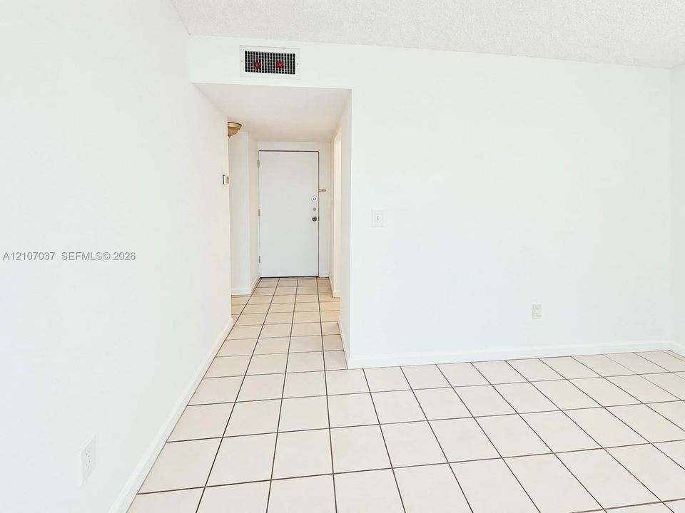 Interior space featuring large-format ceramic tile flooring, neutral walls, and a sliding glass door opening to a private balcony