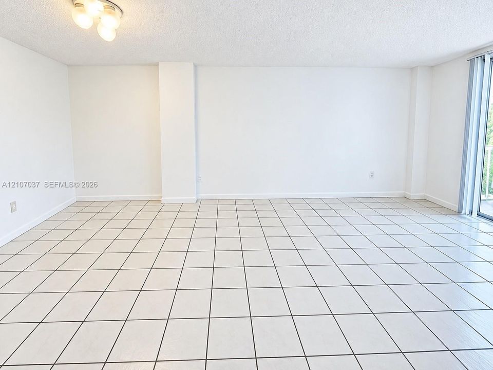 Large open area featuring ceramic tile flooring, neutral wall finishes, and a sliding glass door
