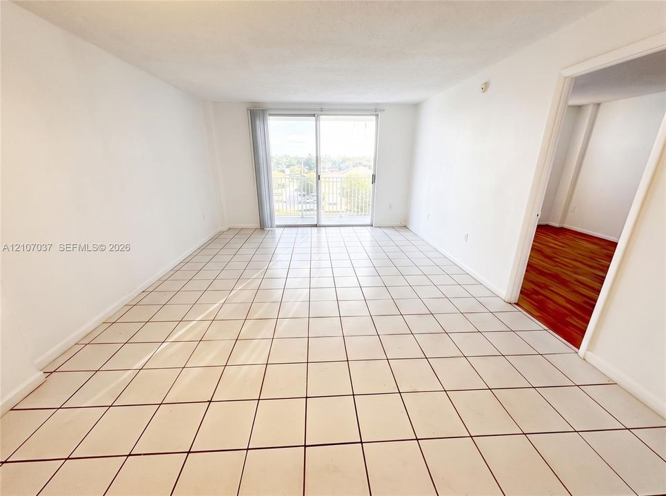 Interior space featuring large-format ceramic tile flooring, neutral walls, and a sliding glass door opening to a private balcony