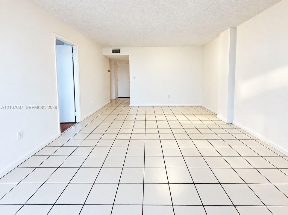 Open-concept interior featuring light-toned square tile flooring, smooth wall finishes, and a neutral color palette