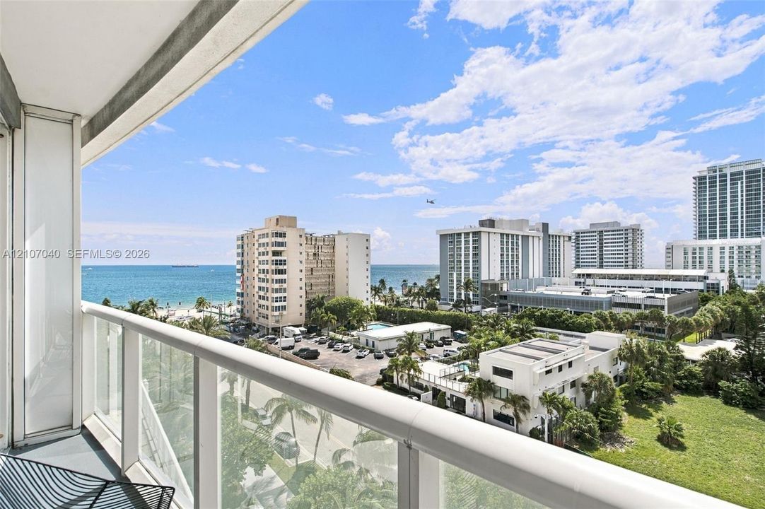 Covered balcony featuring a glass-panel railing and open ocean horizon