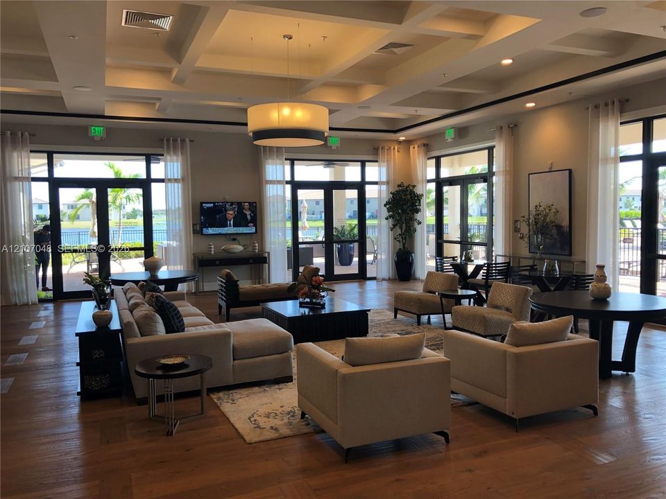 Expansive common area featuring a coffered ceiling, wood-finish flooring, recessed lighting, and large glass-paneled entry doors