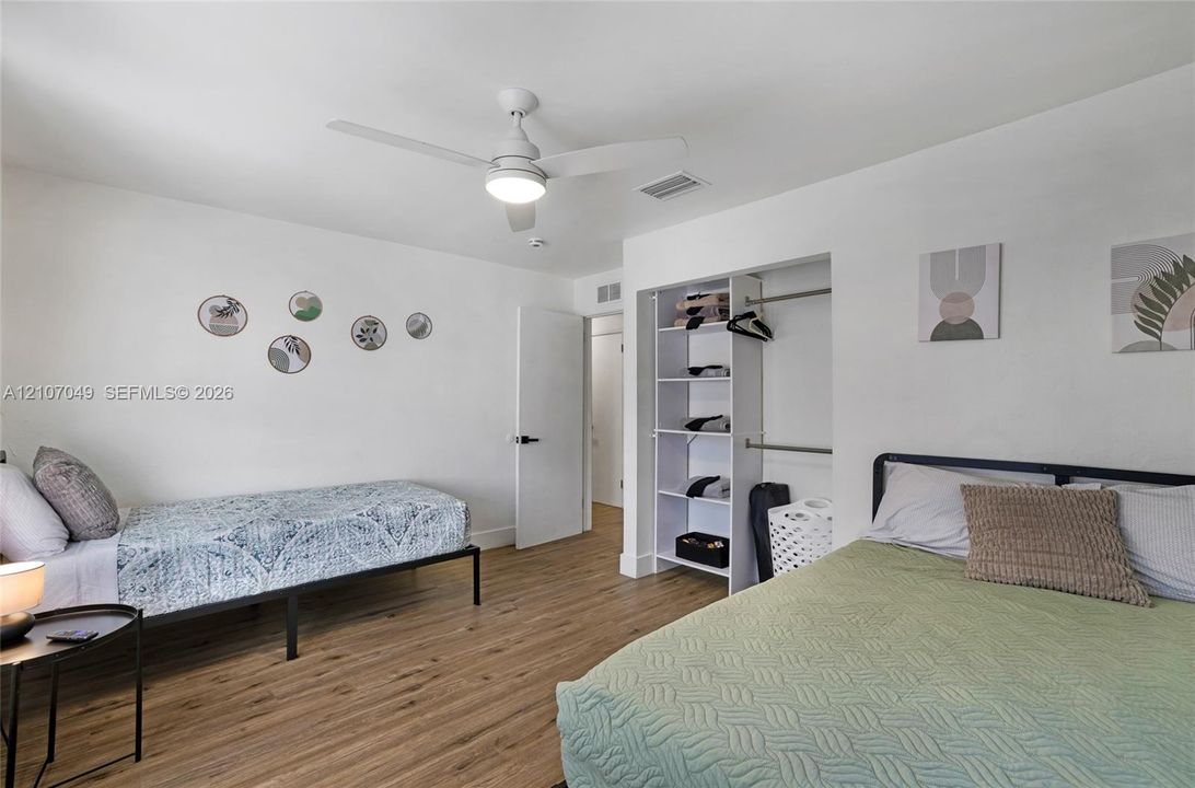 Wood-finish flooring, ceiling fan with integrated lighting, and built-in closet shelving
