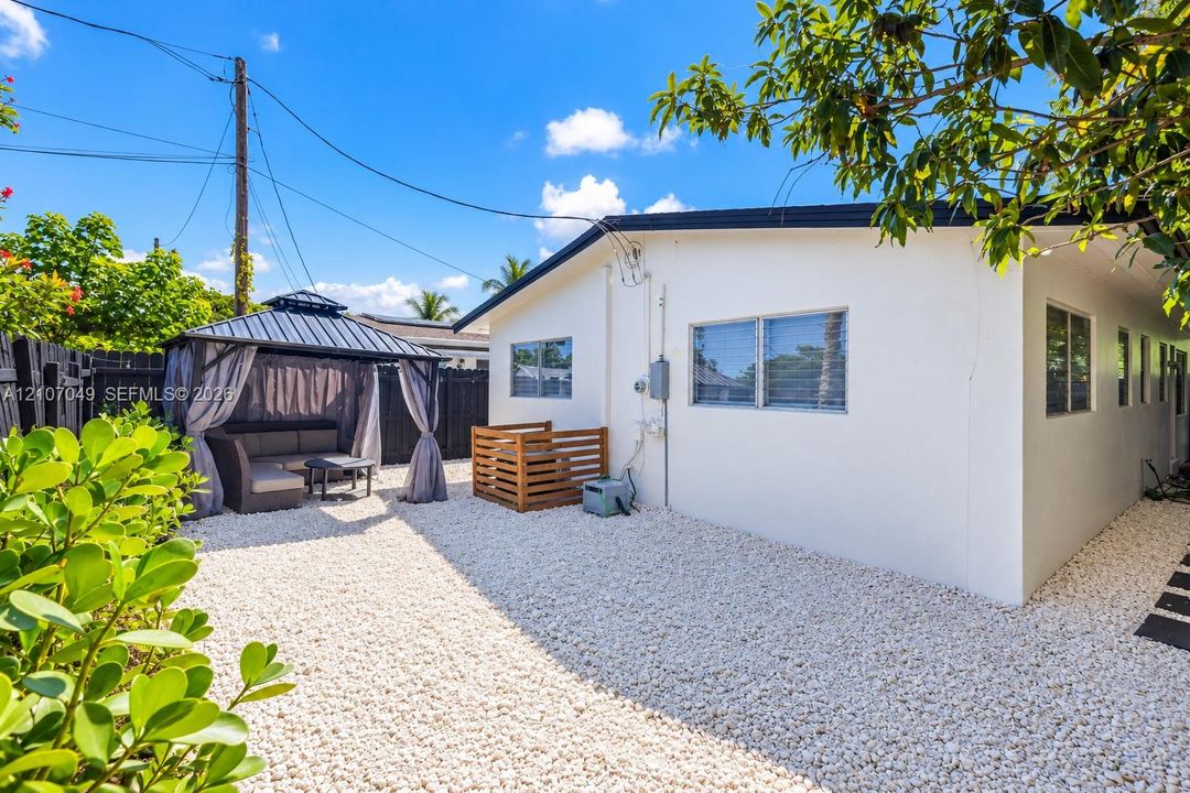 Private backyard featuring a gravel ground cover, a detached metal-frame gazebo, and perimeter wood privacy fencing