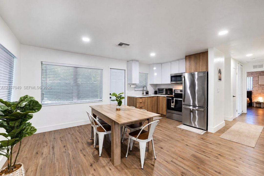 Kitchen featuring two-tone cabinetry with wood-finish lower cabinets, stainless steel appliances, recessed lighting, and wood-finish flooring