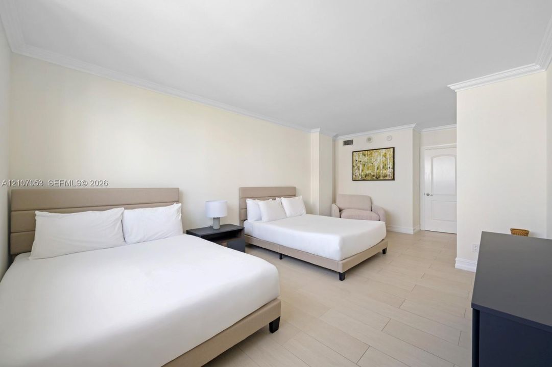 Spacious room featuring neutral wall tones, crown molding, and light-toned tile flooring throughout