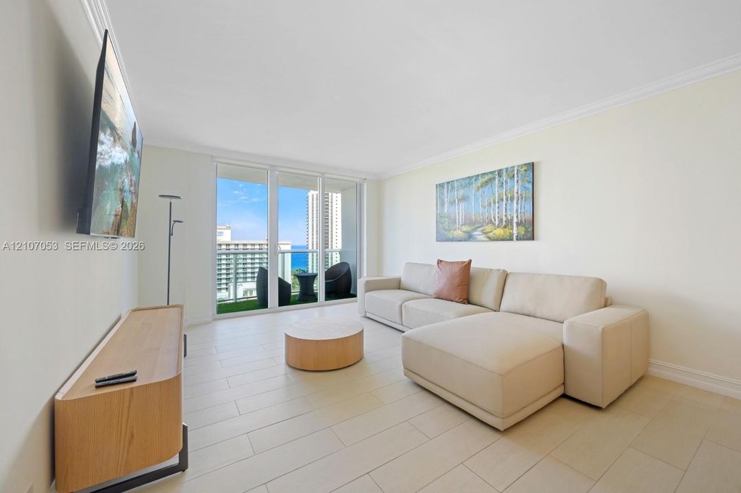 Light-toned tile flooring, crown molding, and floor-to-ceiling glass sliding doors opening to a private balcony