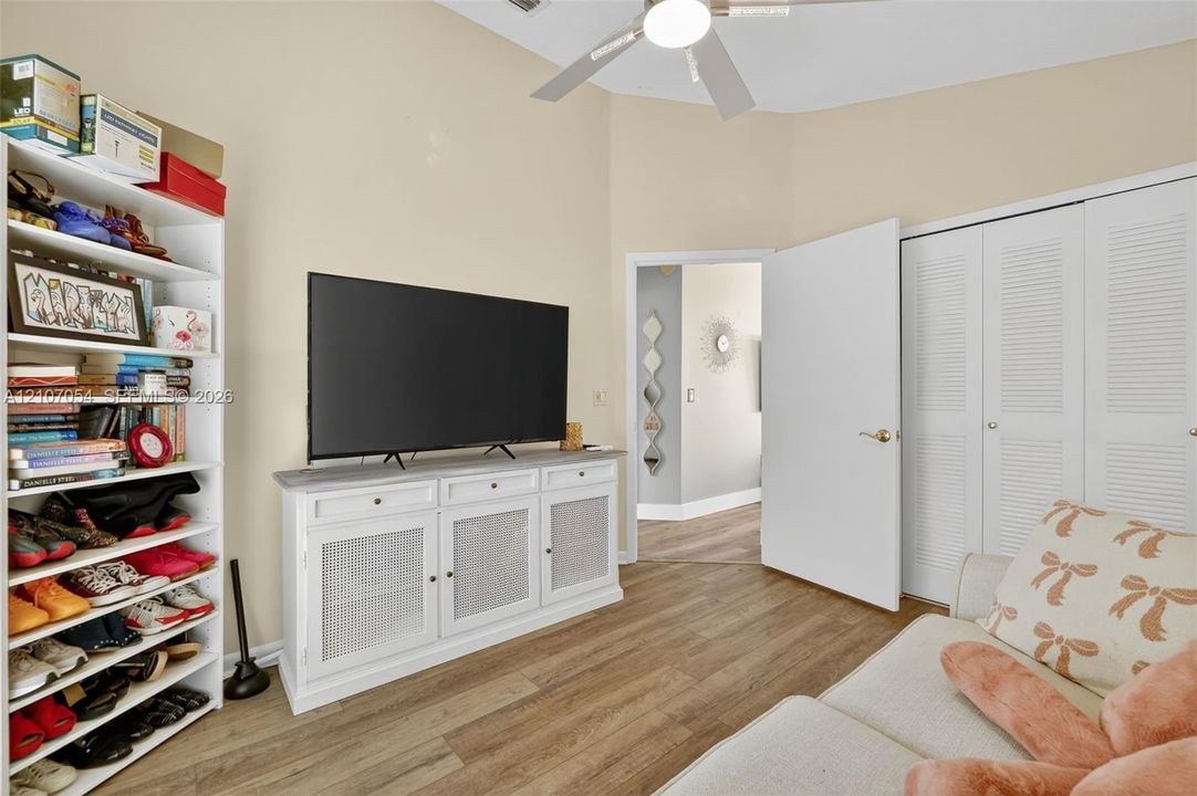 Secondary bedroom featuring vaulted ceilings, laminate flooring and double-door closets with louvered panels