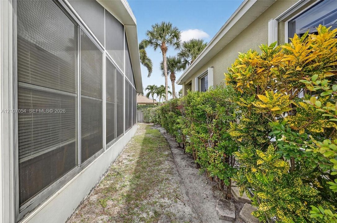 Side yard featuring concrete foundation, stucco siding, and mature landscaping