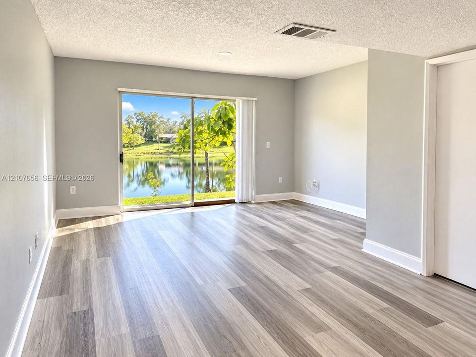 Interior space featuring wood-finish flooring, neutral wall paint, and sliding glass doors opening to a water backdrop