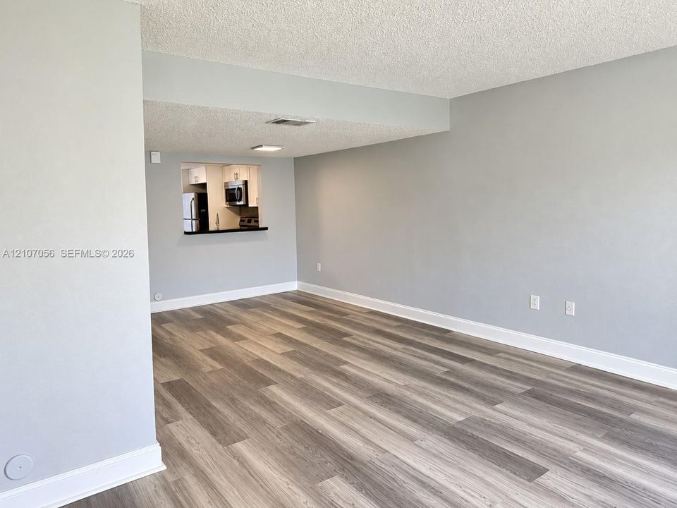 Open-concept interior featuring wood-finish flooring, light grey wall paint, and a pass-through window with a built-in counter