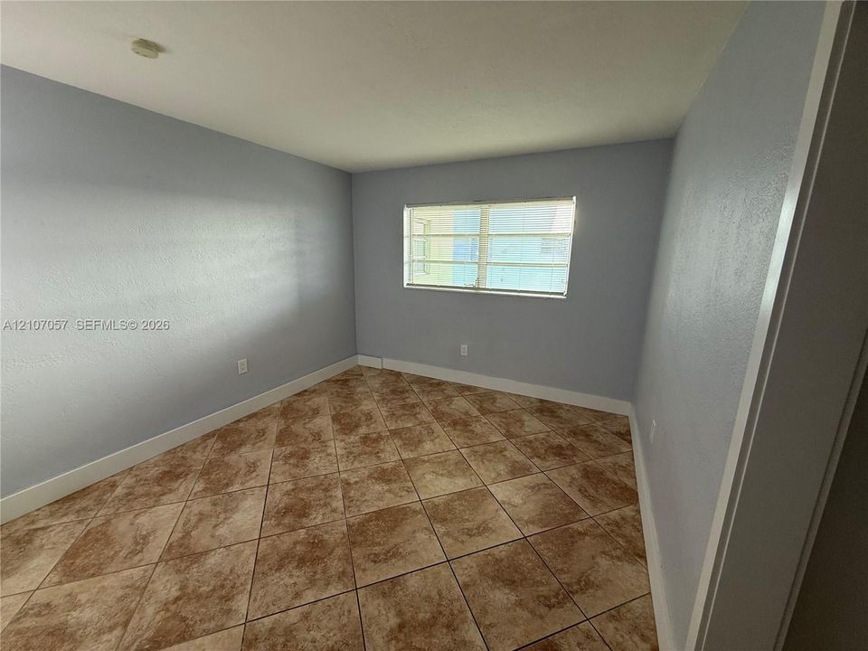 Interior room featuring neutral-toned wall paint, large-format diagonal tile flooring, and a single-pane window