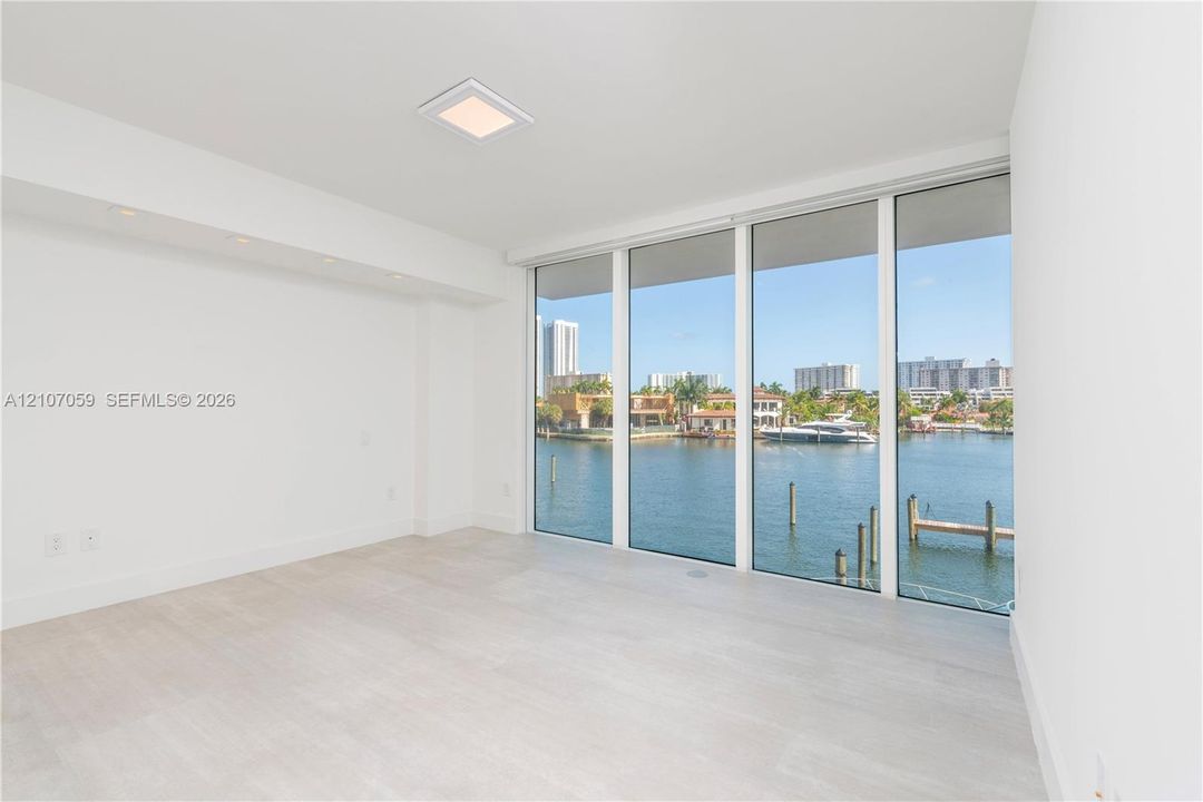 Floor-to-ceiling windows, light-toned wood-finish flooring, recessed ceiling lighting, and waterfront surroundings