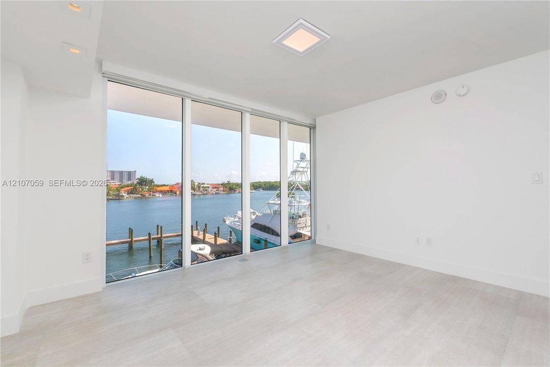 Floor-to-ceiling windows featuring water frontage, wood-finish tile flooring, recessed lighting, and a square flush-mount ceiling fixture